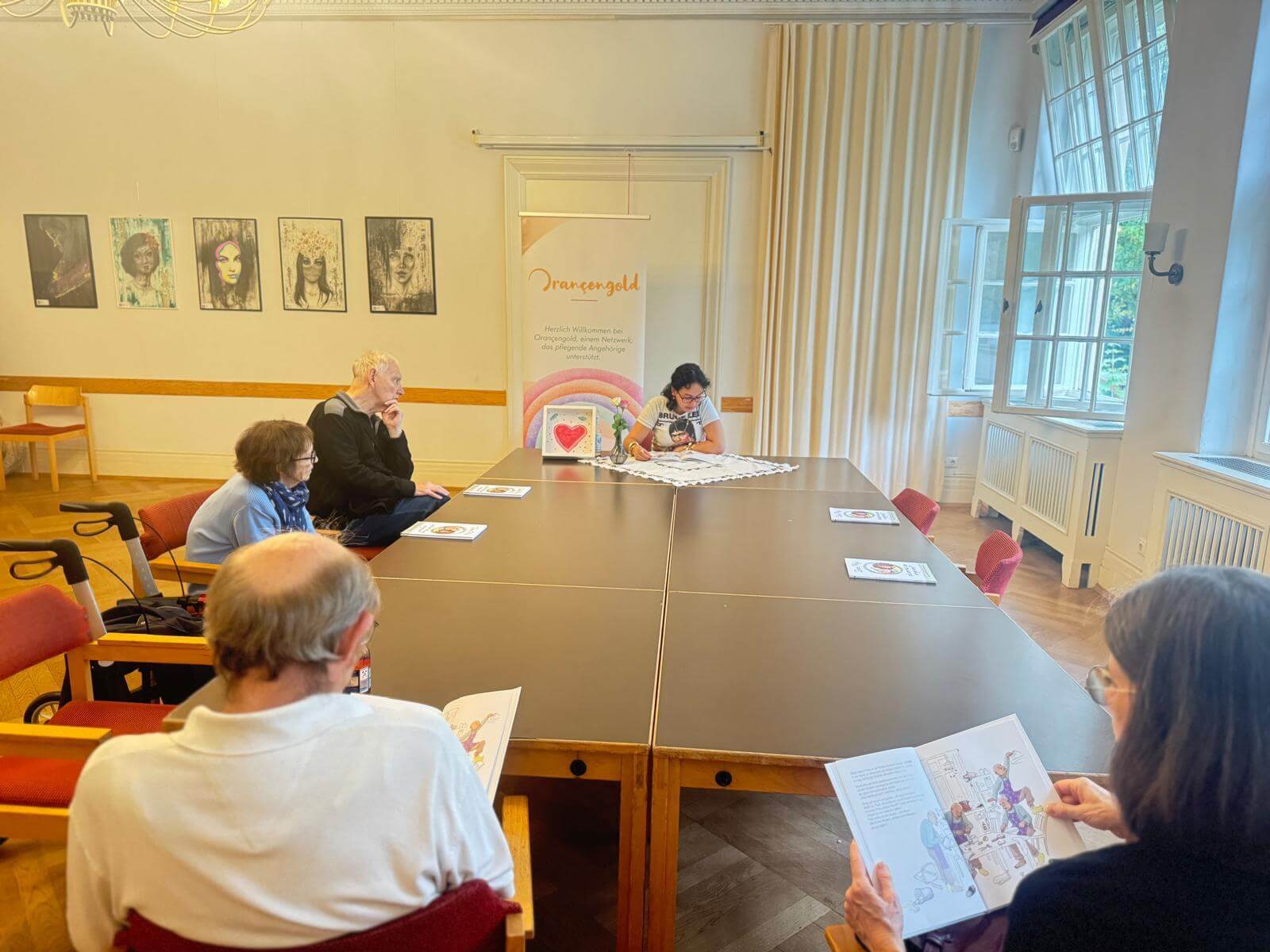 İnsanlar masada oturuyor. Birlikte 'Dede, Phyli ve Kim Kimi Unuttu?' kitabını okuyorlar.